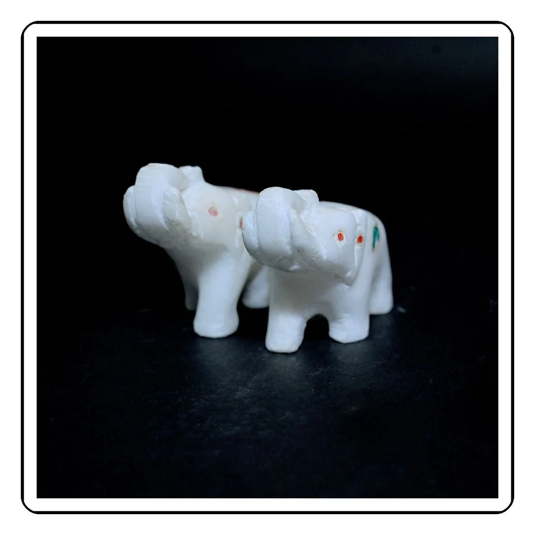 Side view of a hand-carved marble elephant from the decor set, showcasing curved trunk design."