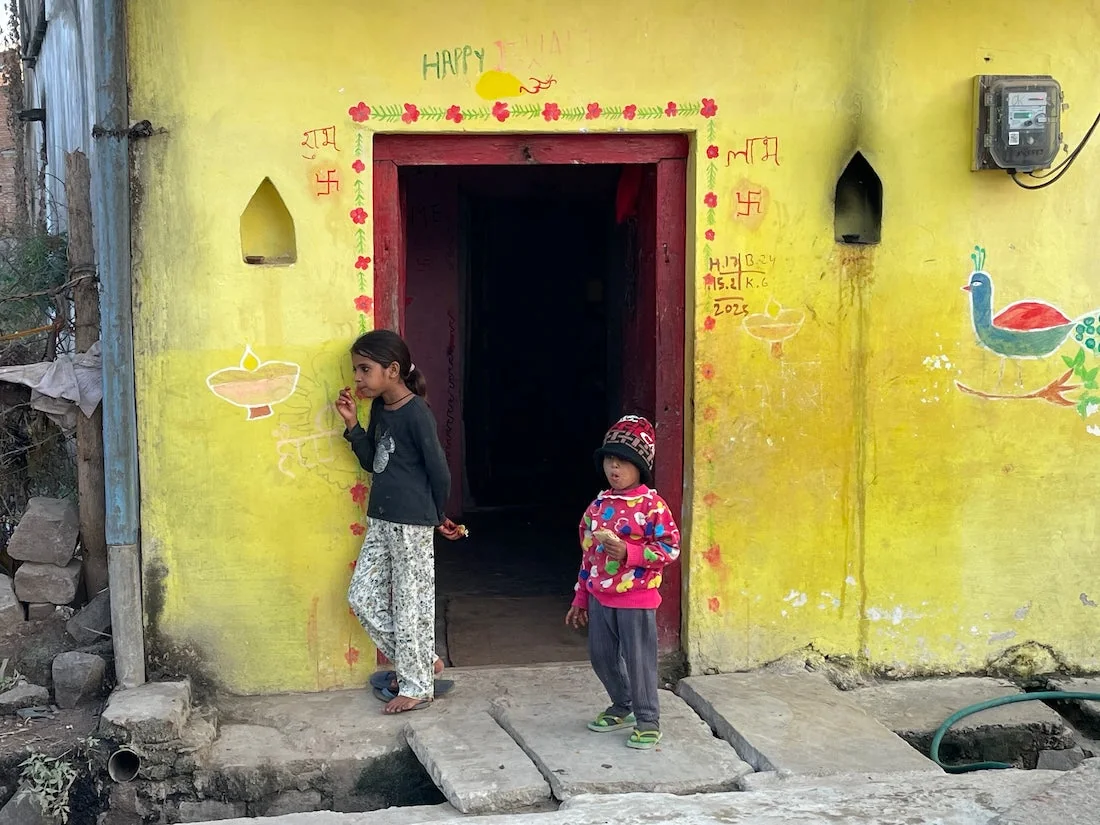 Two Kids in front of a Yellow House